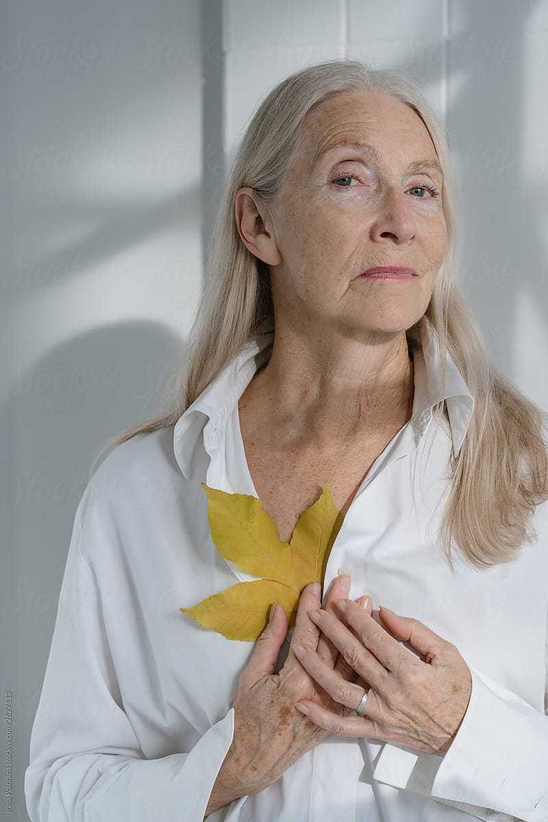 Portrait Of A Senior Woman With Grey Long Hairs With Yellow Leaf By