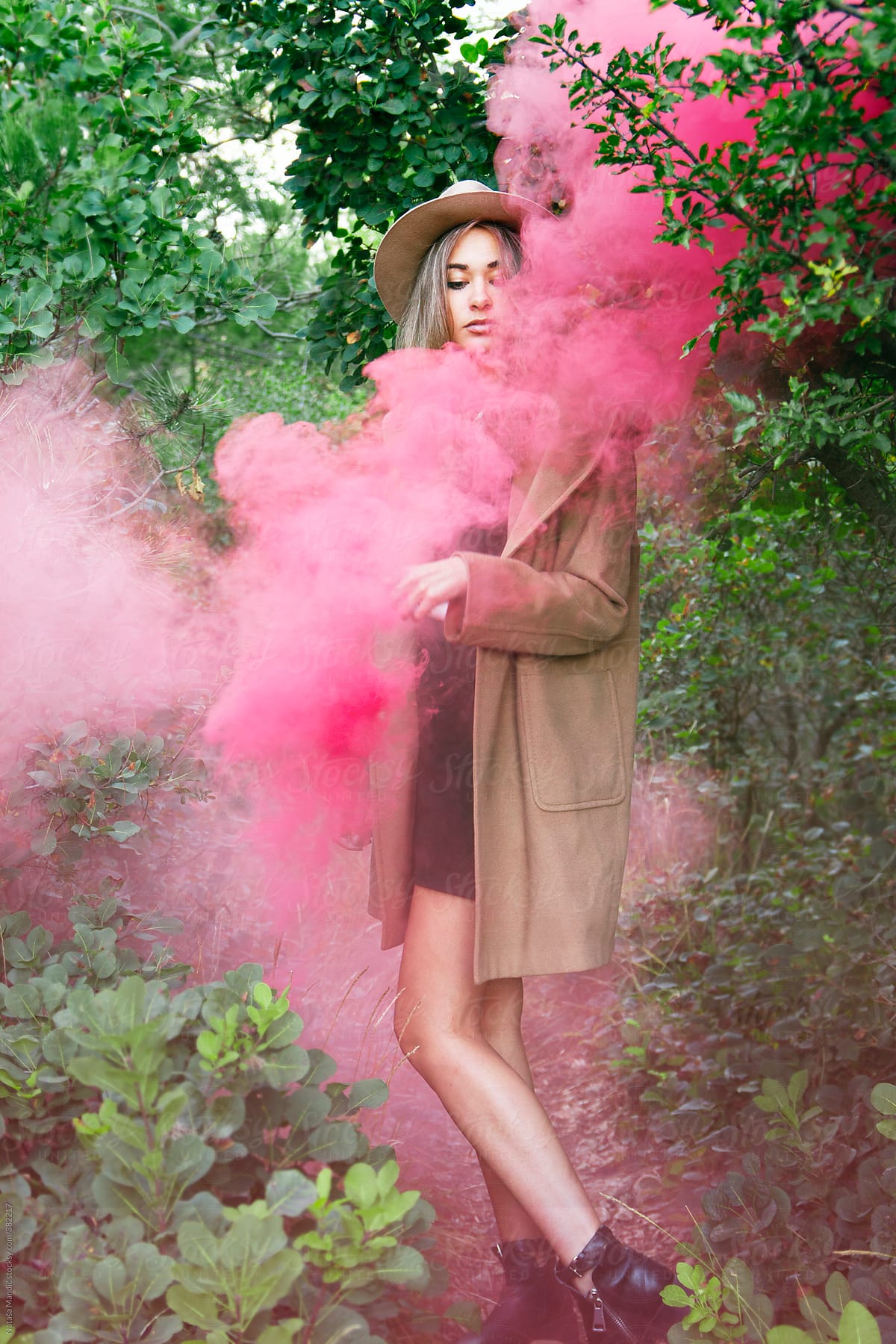 Beautiful woman standing in red smoke in the forest