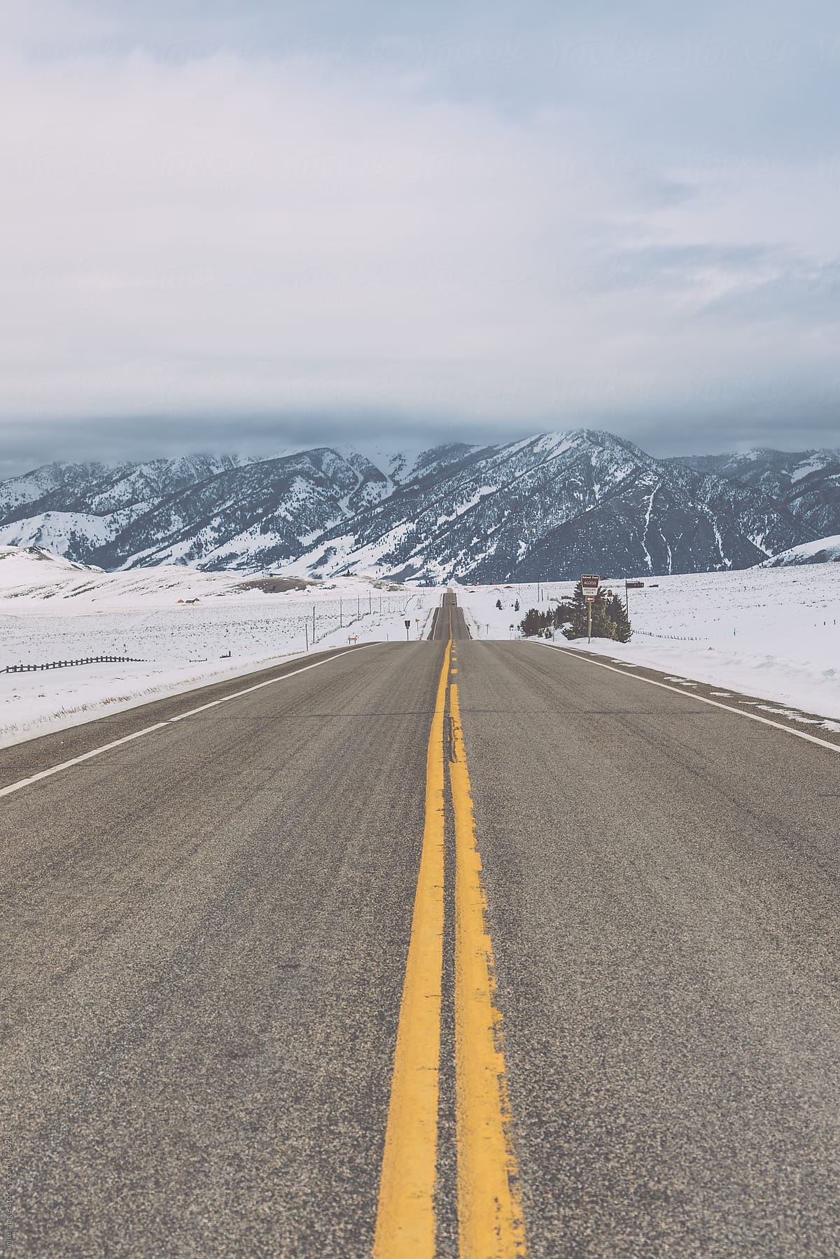 empty two-lane highway toward snow mountain