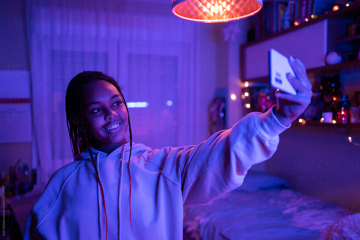 Teen Girl Taking A Selfie In Her Bedroom At Night.