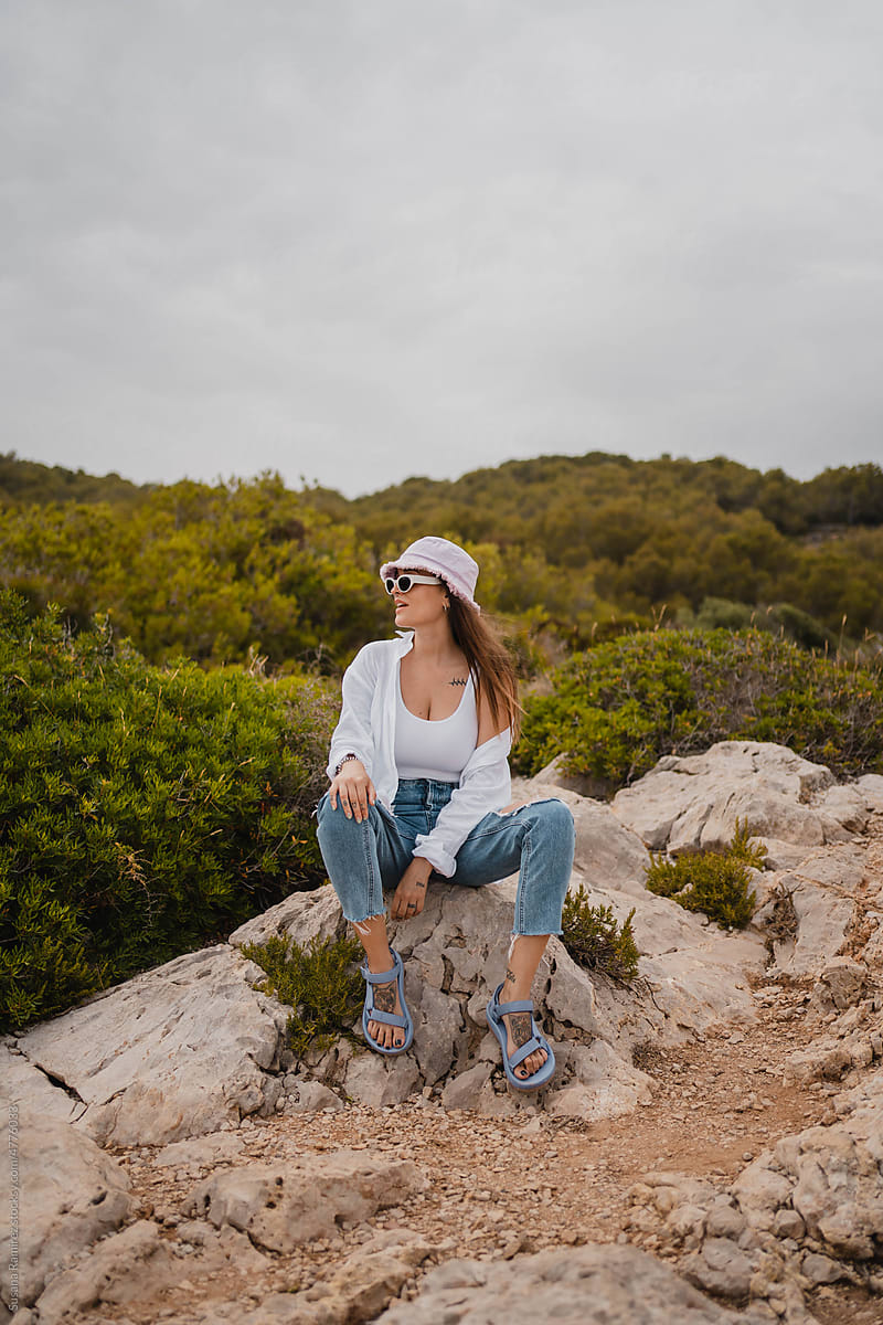Brunette modern woman sitting on a rock