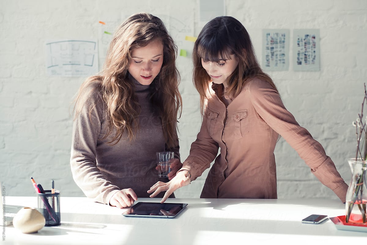 Two young women working together with a tablet PC.