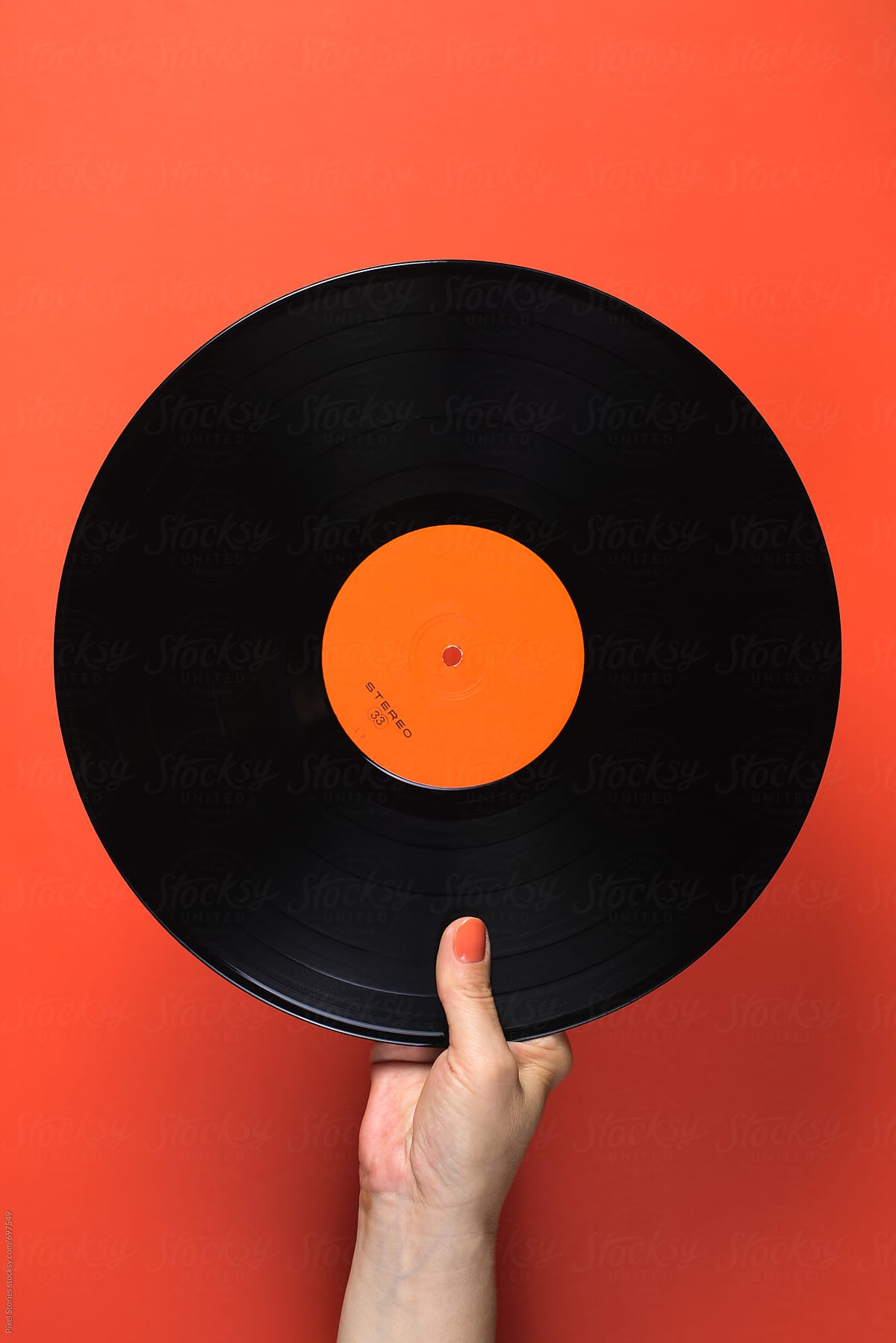 Hand holding orange vinyl record on orange background