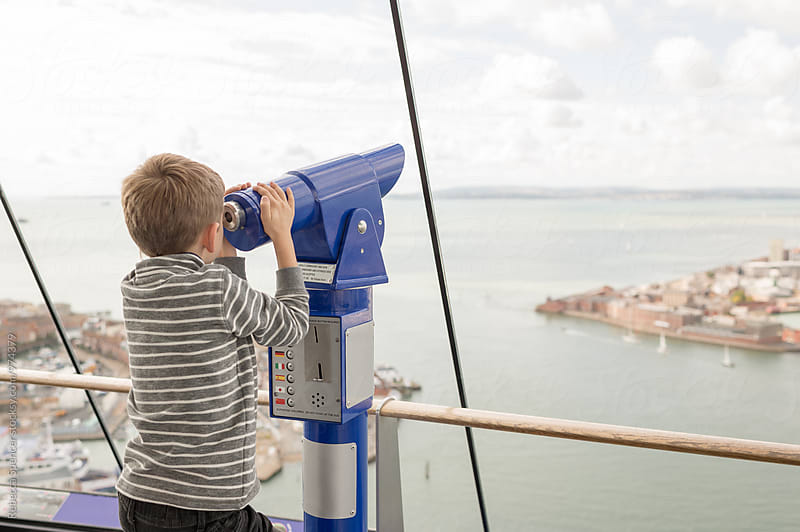 Child looking through a coin operated telescope on an observation deck