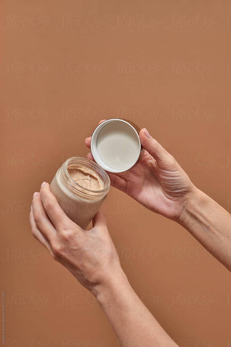 Crop female opening jar with cosmetic product scrub
