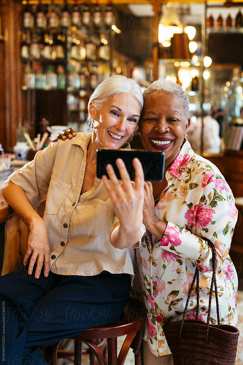 Cheerful mature women taking selfie in cafe