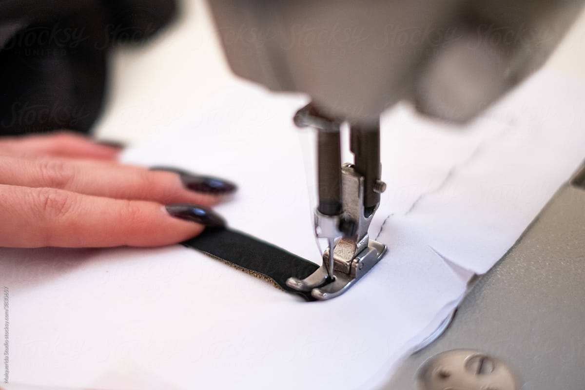 Close up of a tailor using sewing machine in an atelier