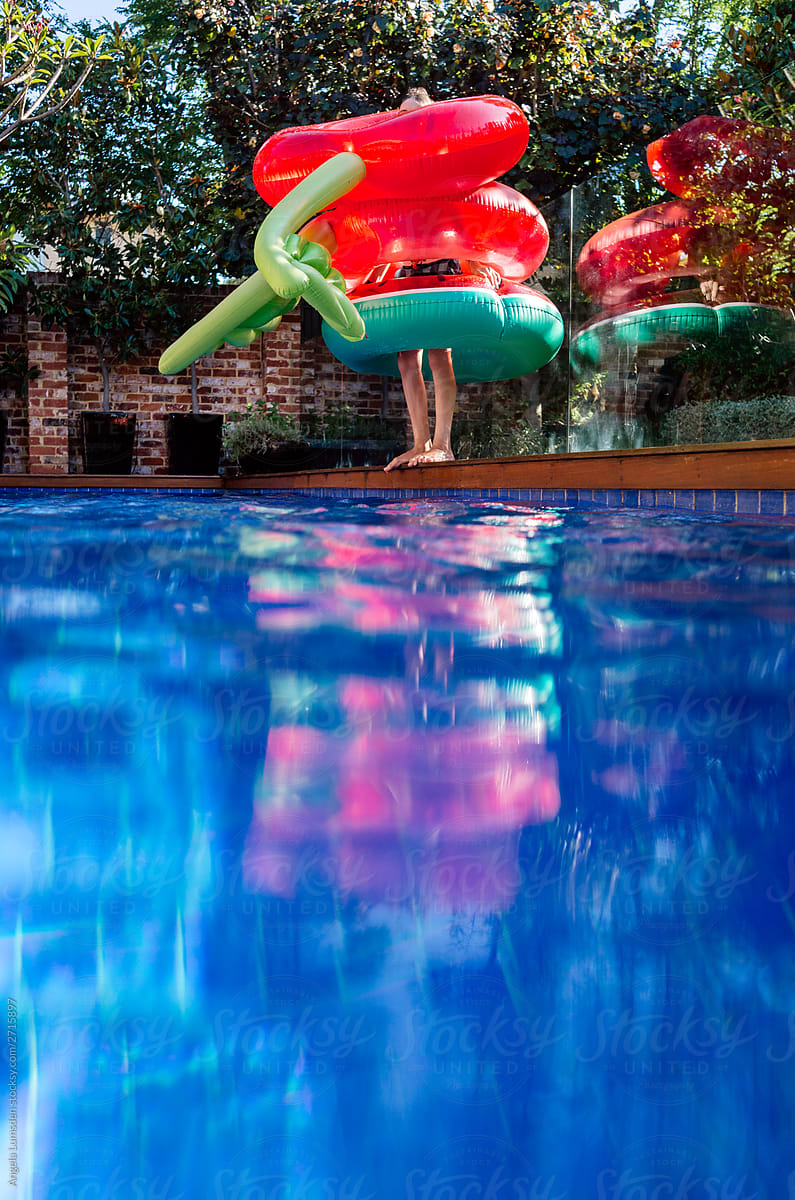 Person wearing three pool inflatable rings beside a pool
