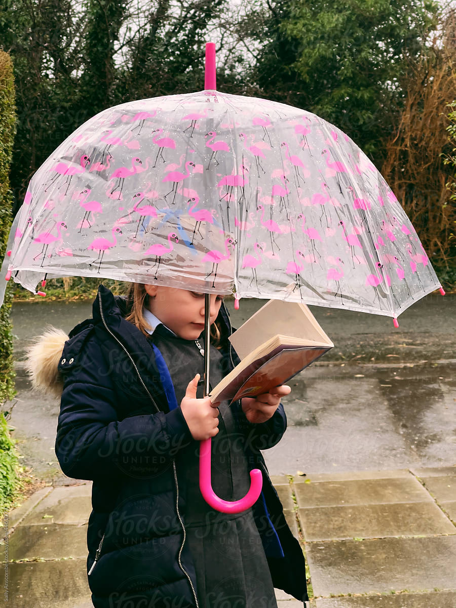Little girl reading a book while outdoors on a rainy daY