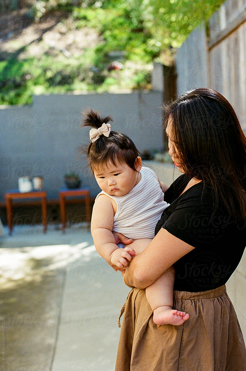 Asian mom holding chunky baby outdoors