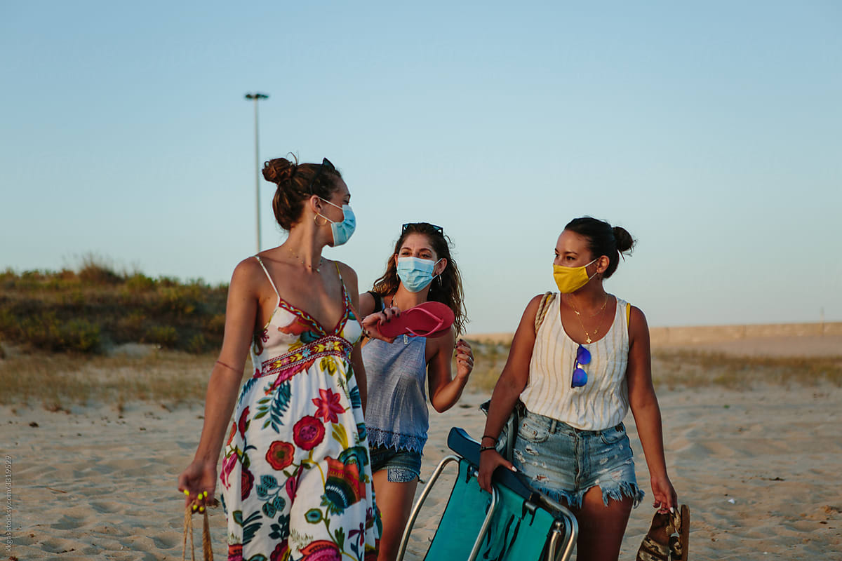 Three women walking on the beach with their belongings
