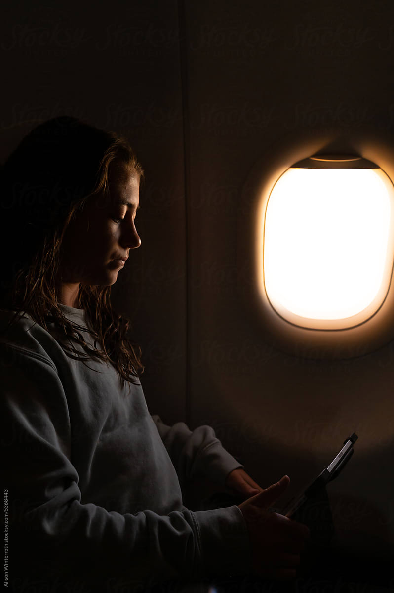 Girl watches tablet as plane flies