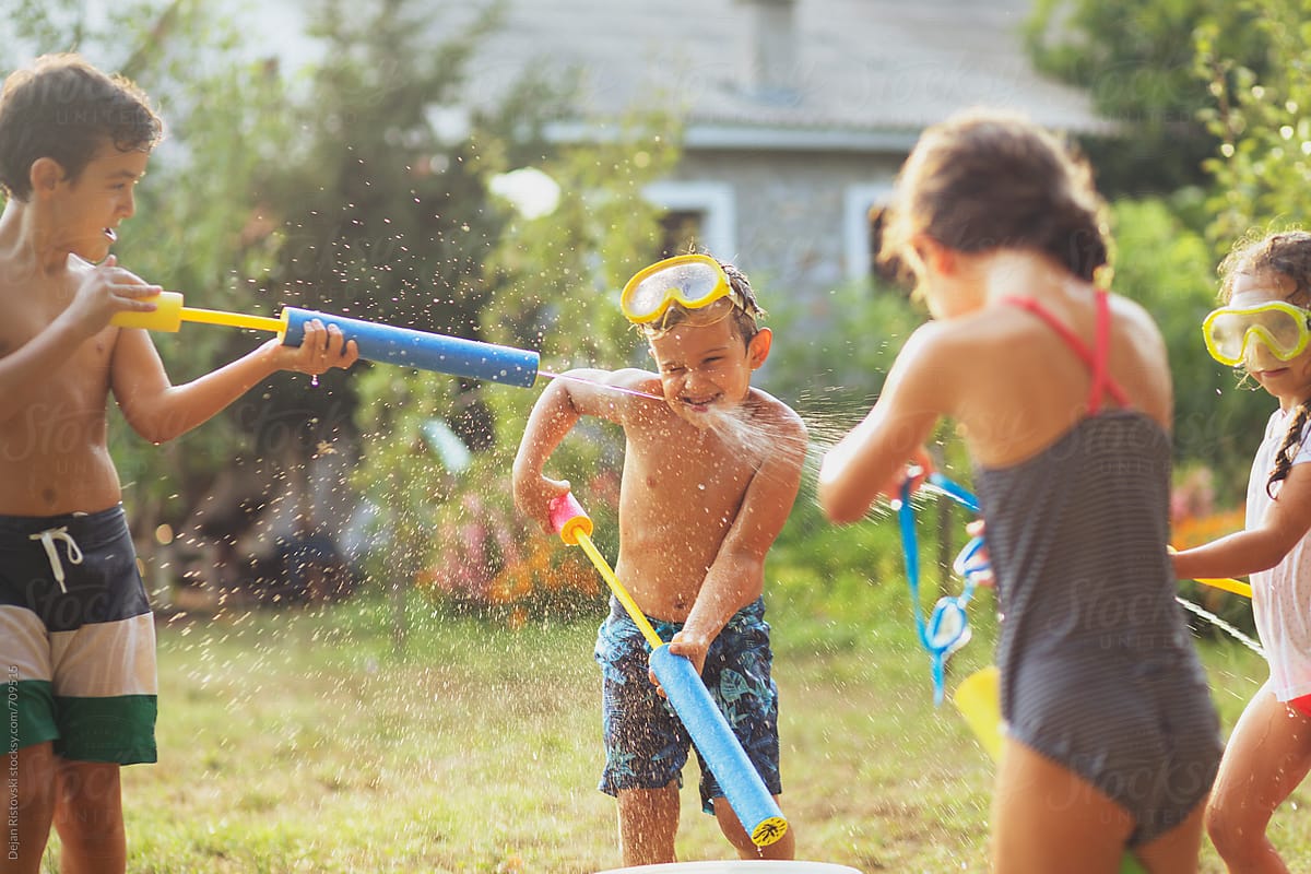 Children playing with water guns in the yard.