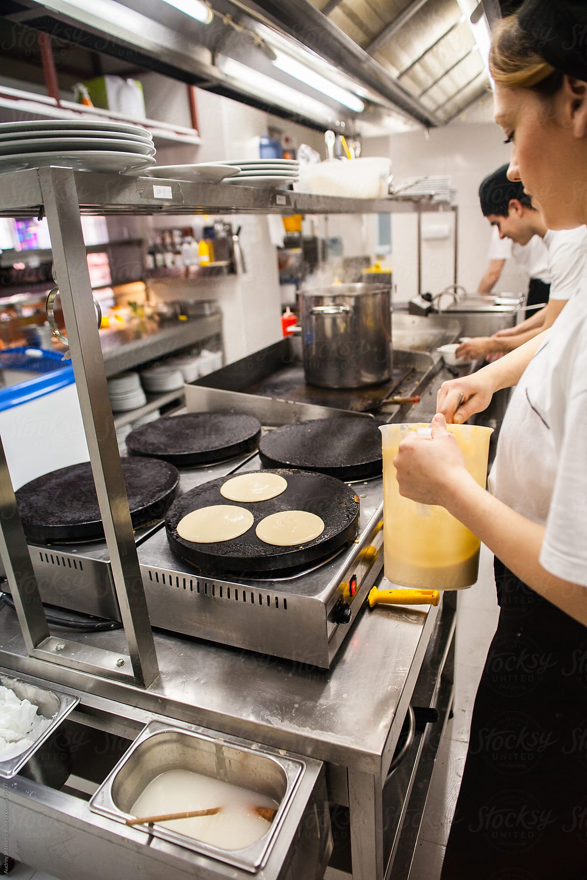 Team of chefs preparing food in a commercial kitchen.