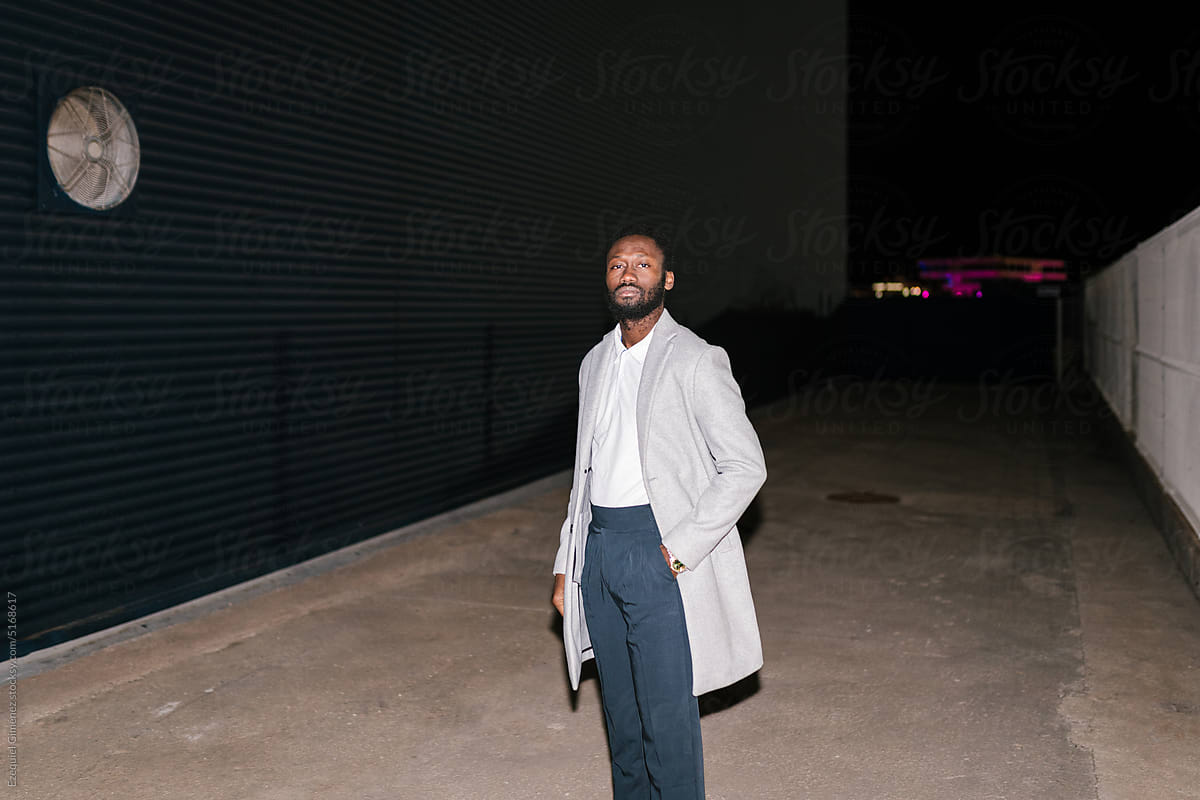 Stylish man standing on street at night