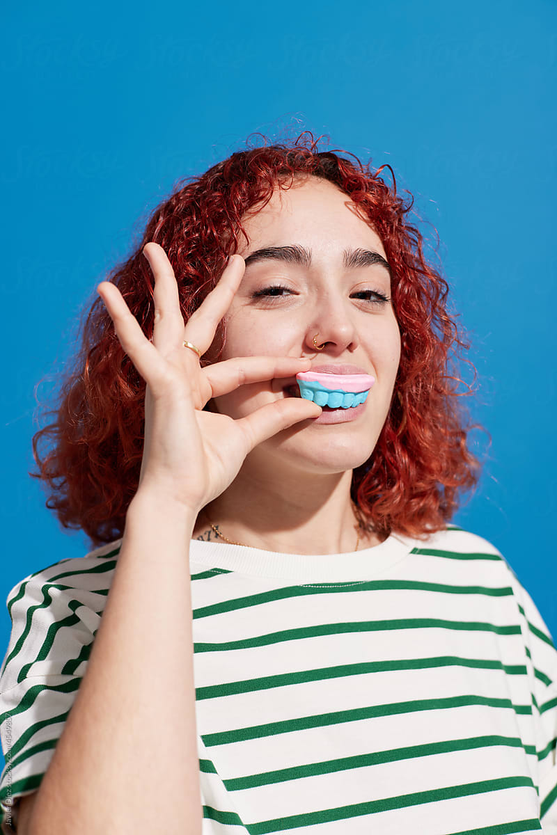 Content ginger woman eating candy in studio