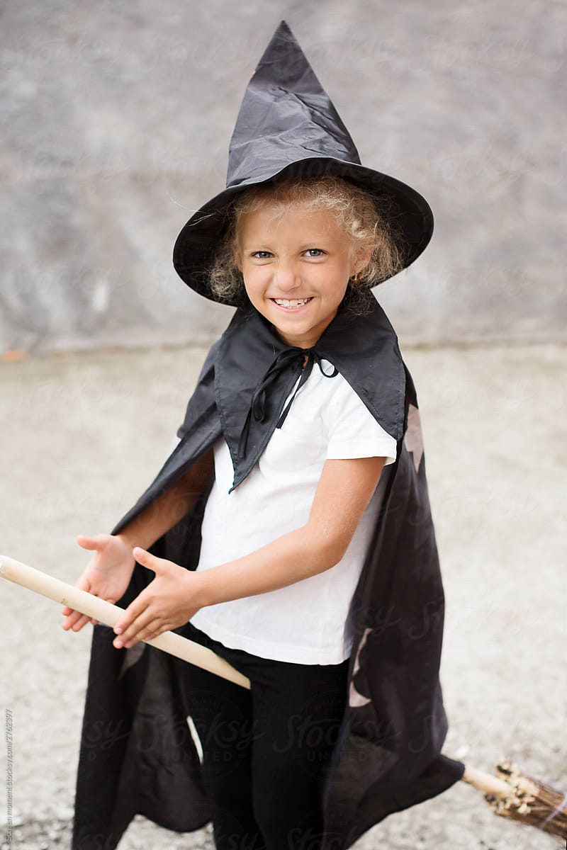 Girl in Halloween costume having fun. A little girl in a witch costume is playing outdoor. Little girl witch  costume with a broom