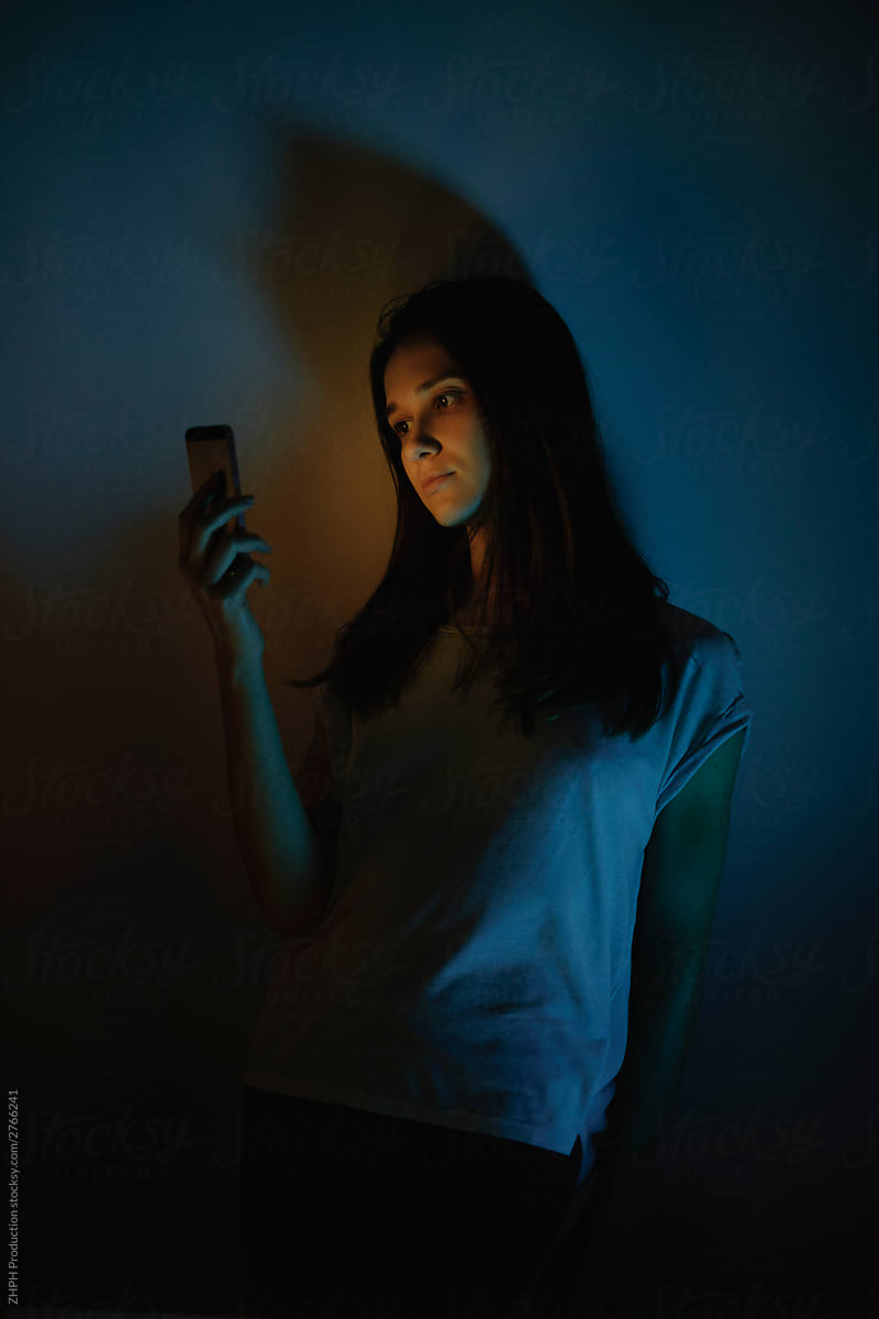 Young woman lit with smartphone screen light