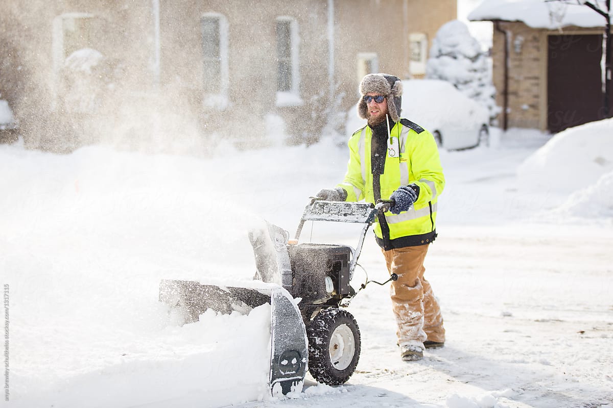 Man using a snow blower to clean his walkway.