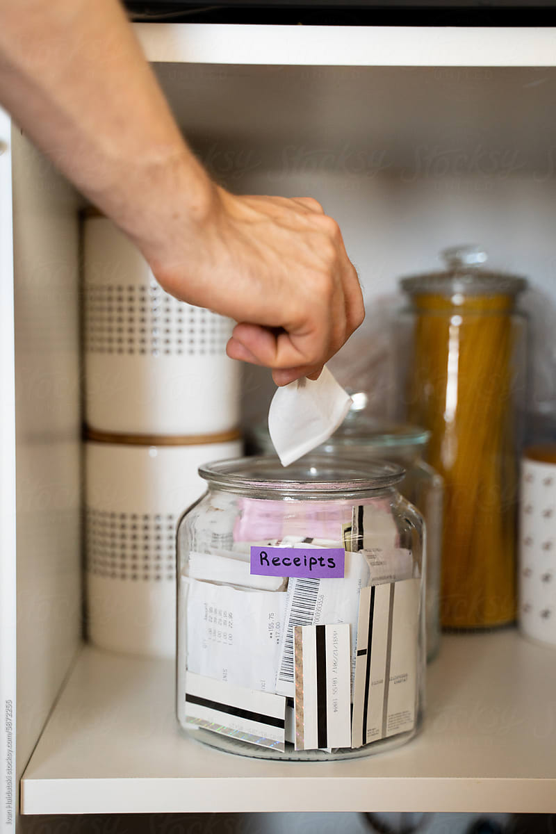 UGC, an unrecognizable male hand putting receipts into a glass jar