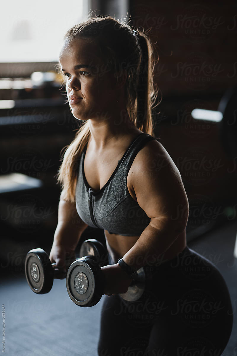 Dwarf woman goes in for sport and makes exercise with dumbbells.