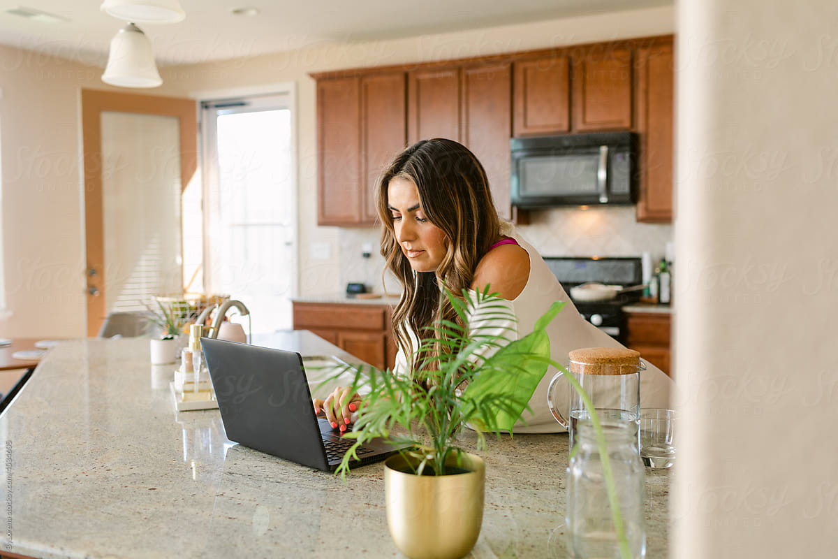 Woman working on laptop in kitchen