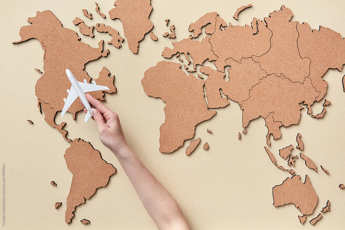 Woman holding plane miniature above brown map