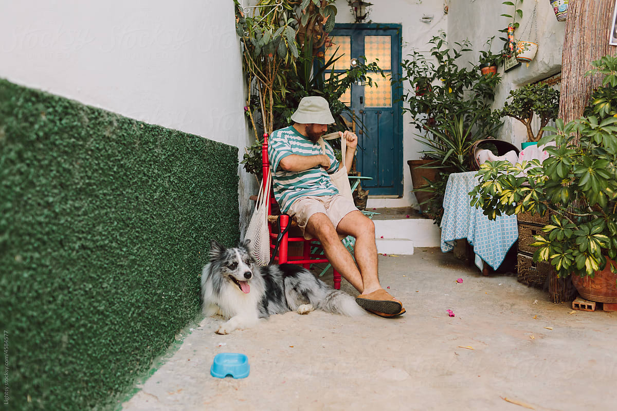 Man sitting in front of a door house with his dog