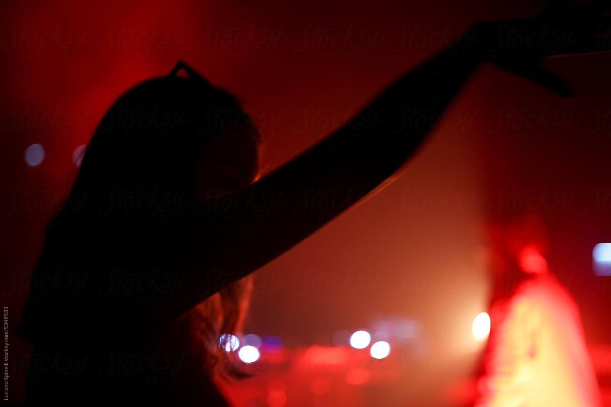 Woman shadow silhouette raising arm at red neon party in Brazil