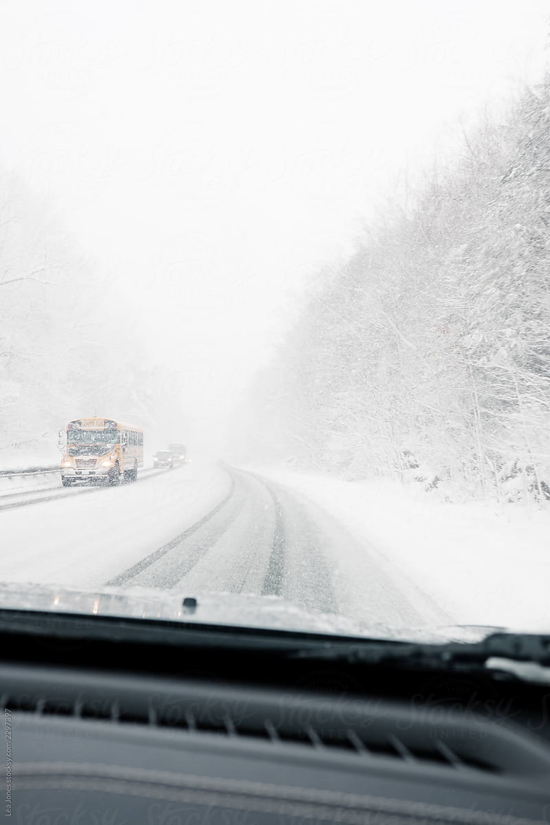 view from the car during a snowstorm, with school bus on the road