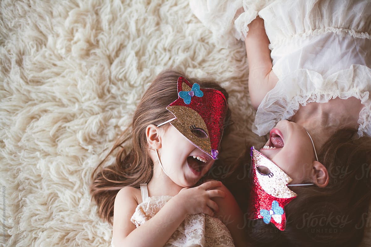 Sisters laugh together wearing sequined fox masks