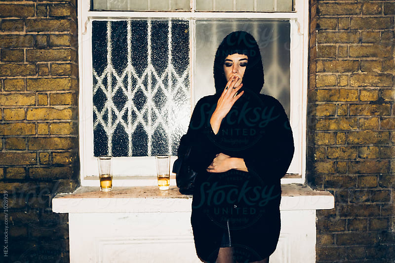 Young Beautiful Woman Smoking a Cigarette out of a Pub in London Uk