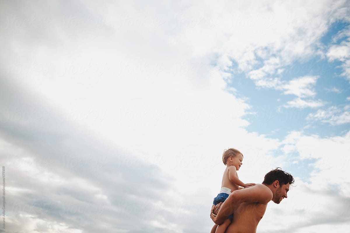 Young dad having fun with toddler son on tropical beach - shoulder ride