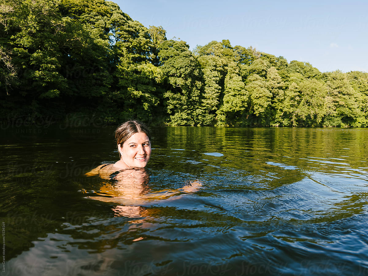 Happy wild swimmer in the river at sunset