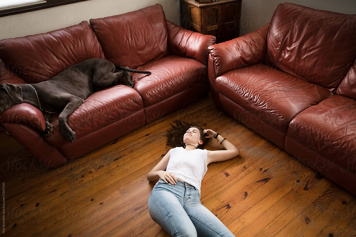 Relaxed young woman on the floor with dog on the sofa