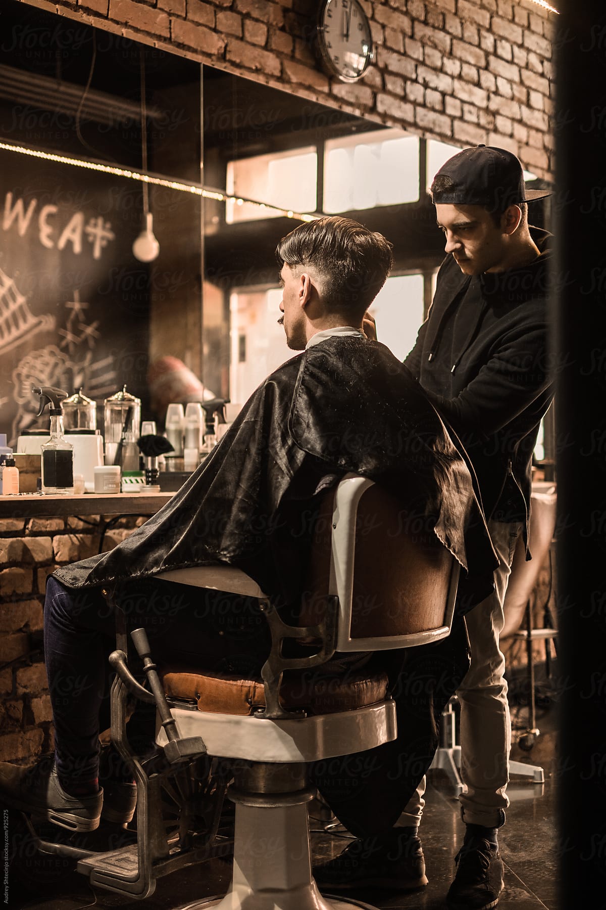 Young barber giving client a classic haircut in vintage barber shop