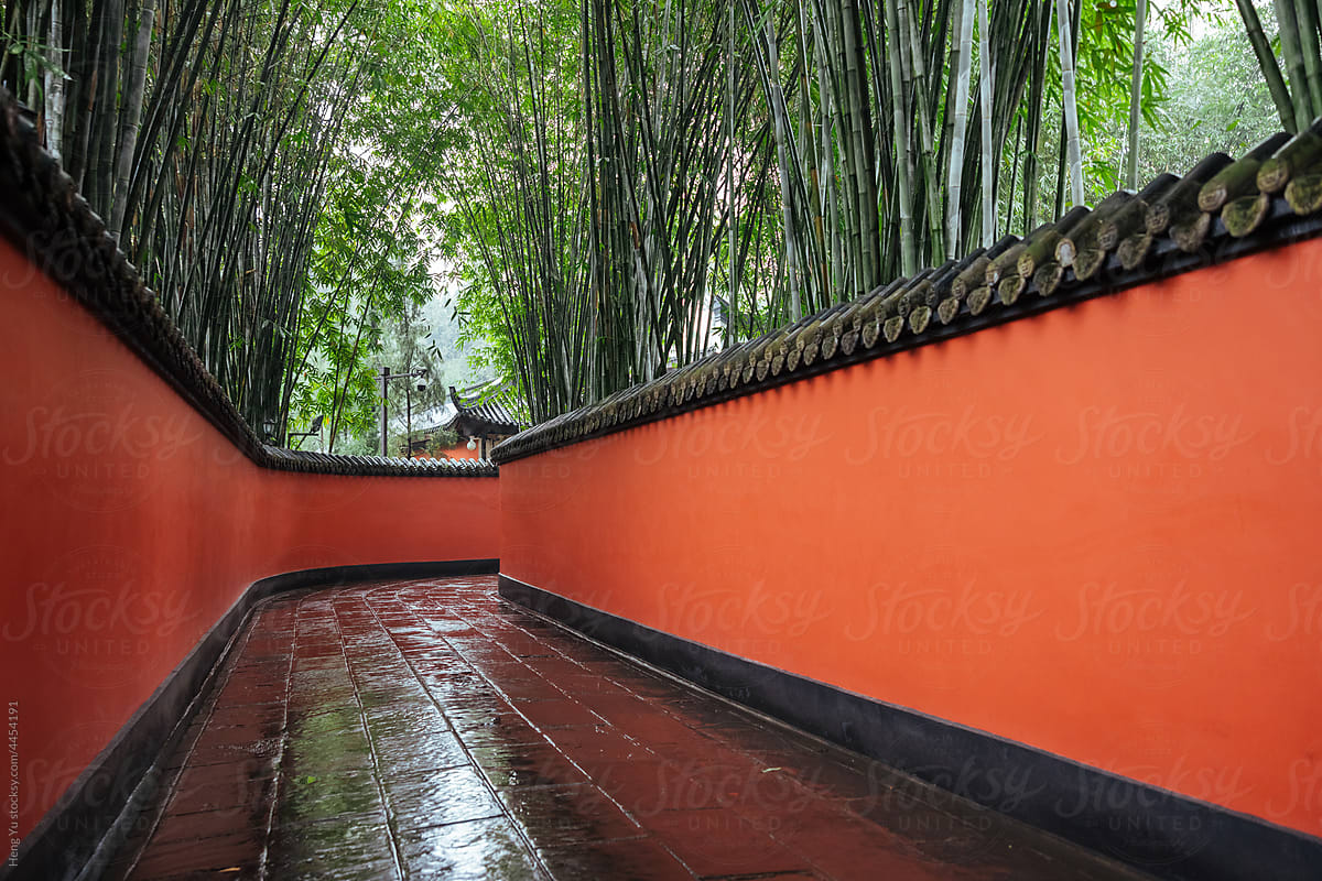 Passage between red walls surrounded by bamboos