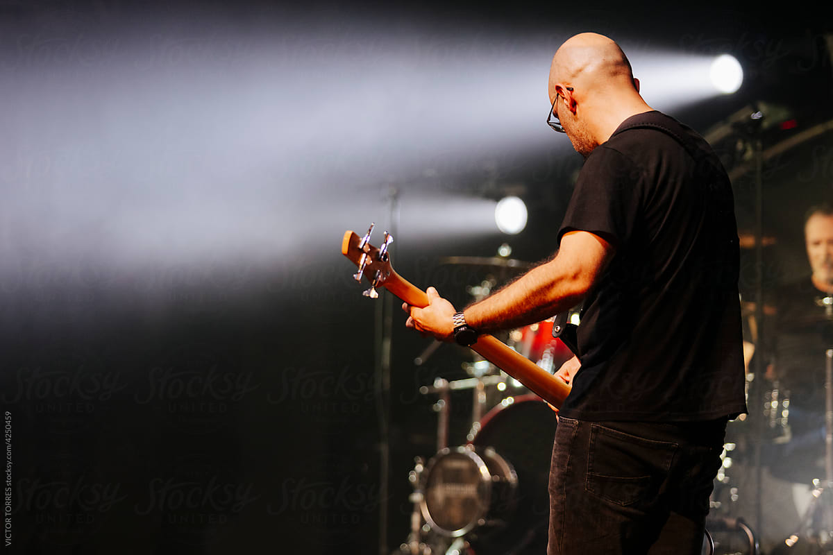 Bald musician playing bass in live concert