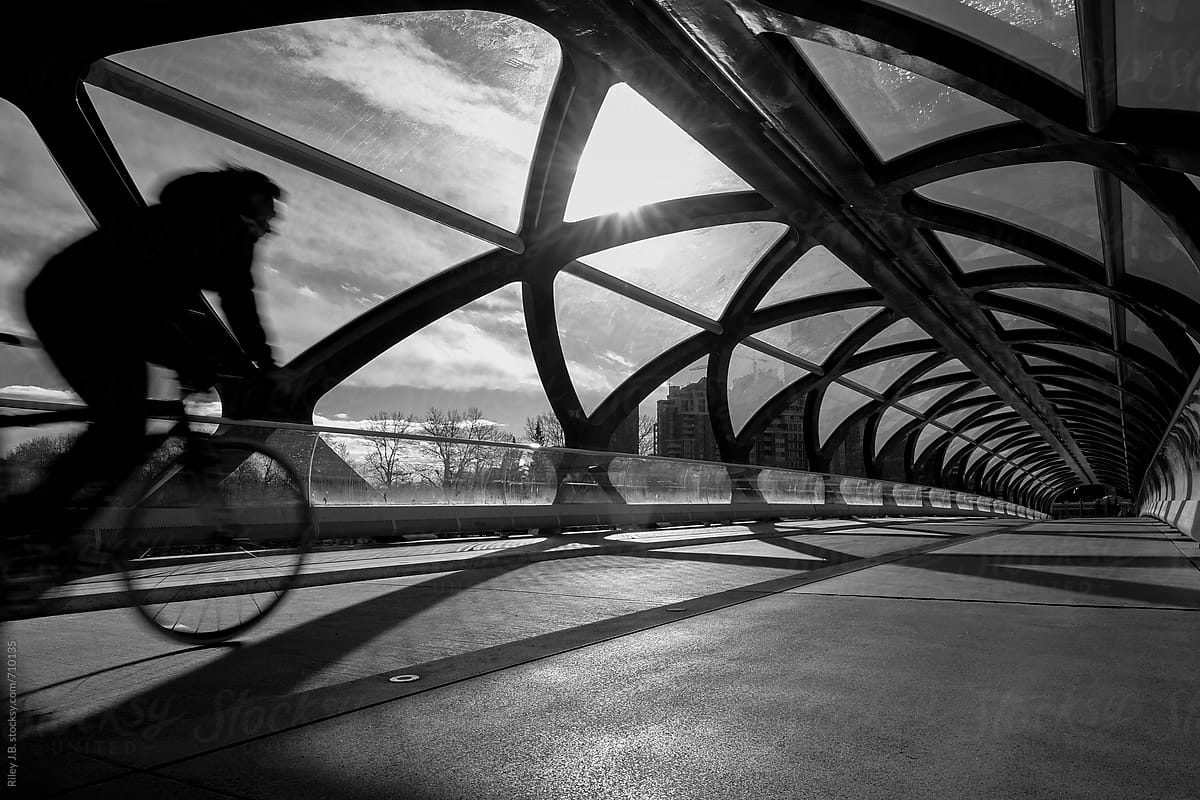 Cyclist rides over modern pedestrian bridge