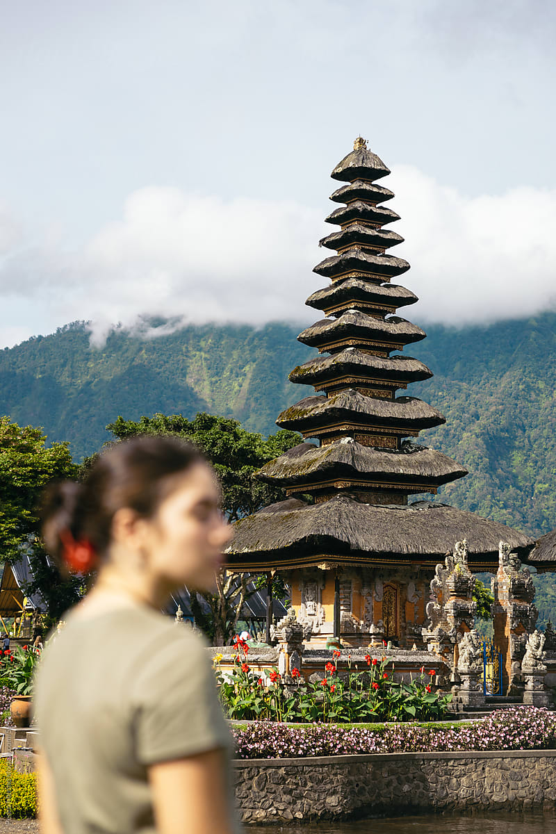 Woman visiting an Hindu Temple surrounded by mountains in Bali