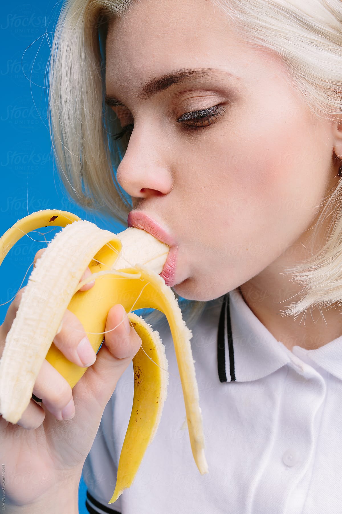 Blonde girl eating banana seductively by Javier Díez - Stocksy United