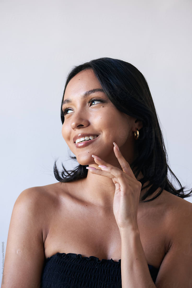 Laughing Latina Model Has Hands to Her Face Featuring Glowing Skin