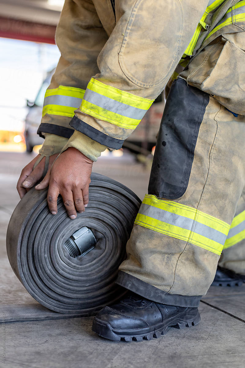 Close Up Of A Firefighter Coiling A Water Hose