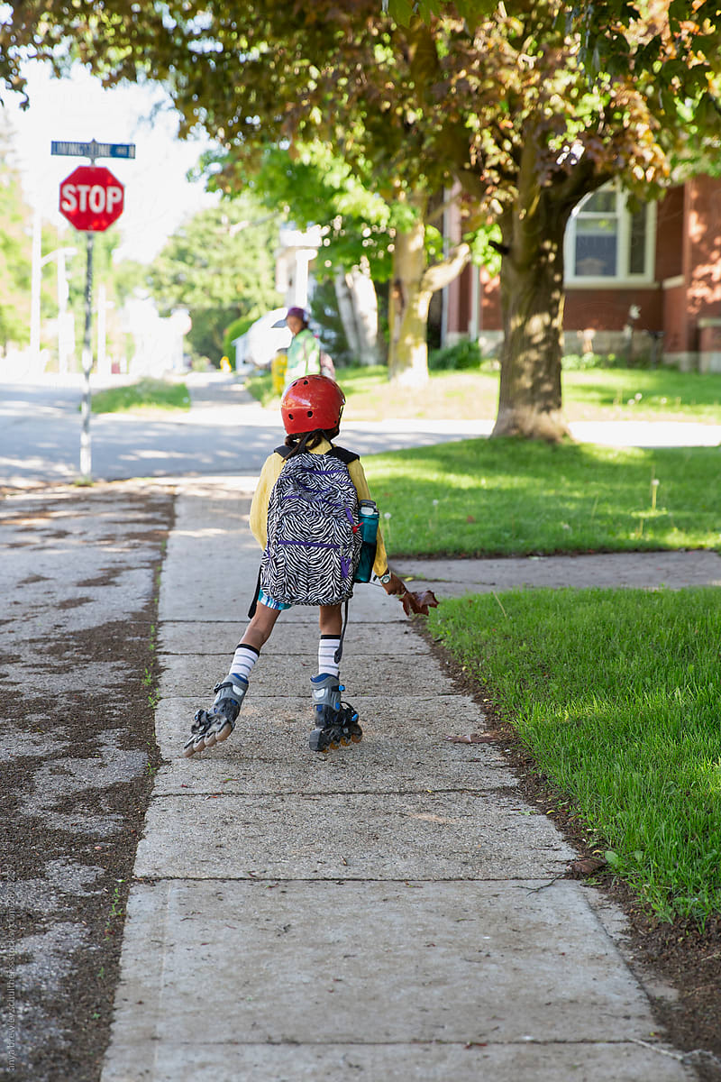 Young girl with backpack roller skating to school