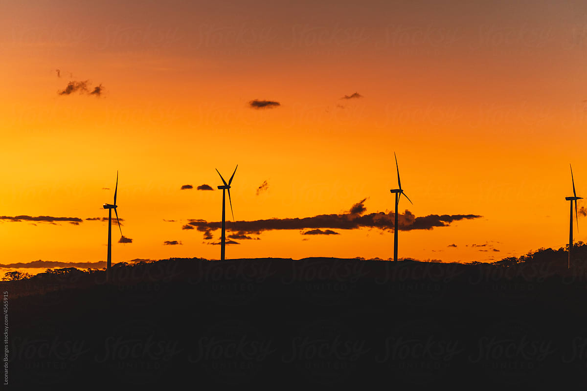 Sunset with wind towers rotating and generating energy.