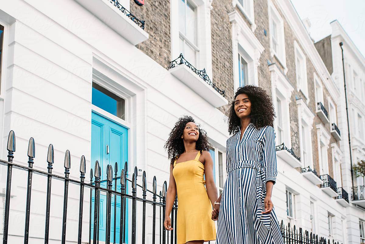 Two black women holding hands walking in the street