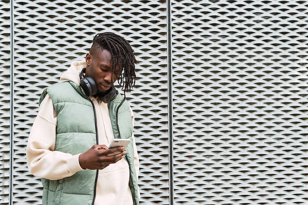 Black man with headphones browsing smartphone