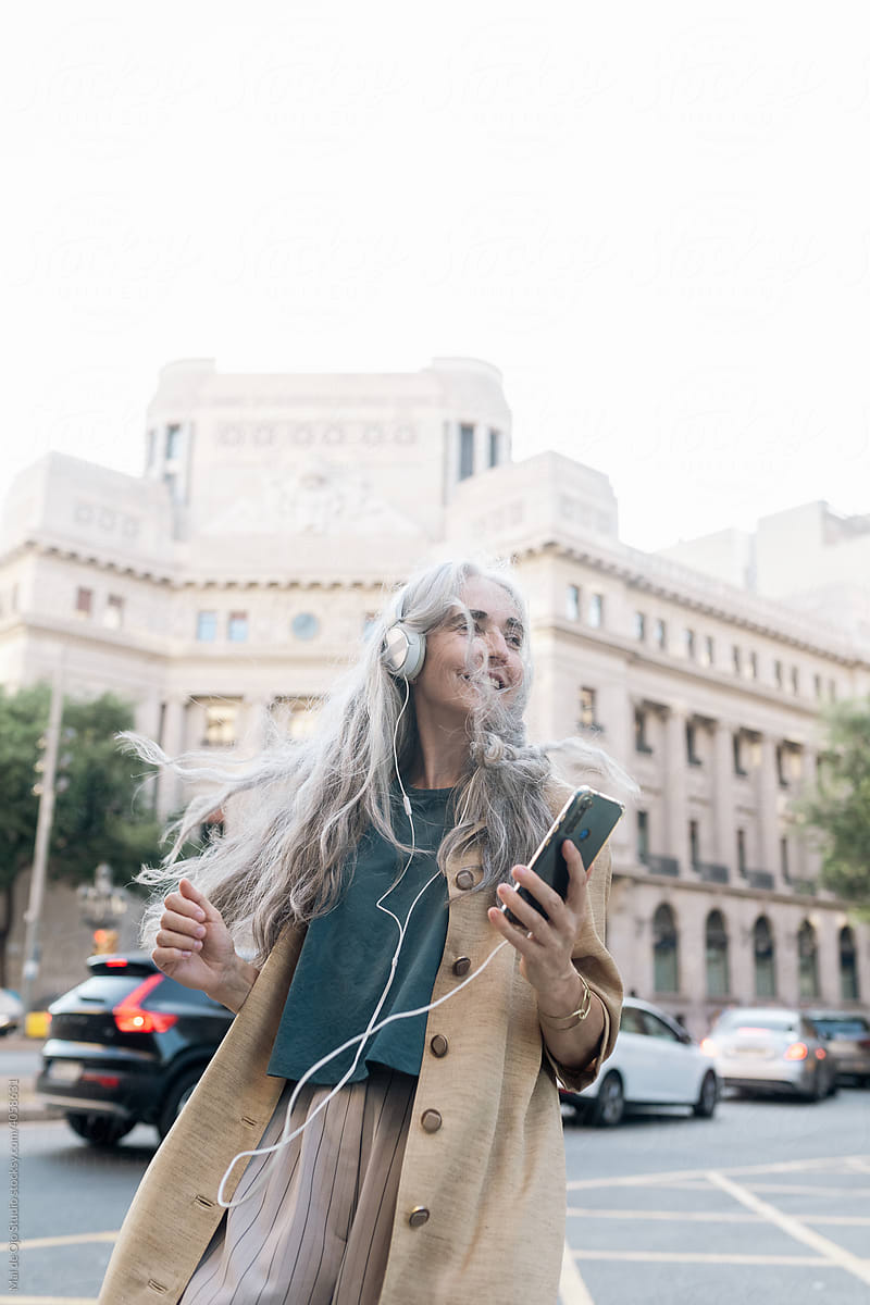 Grey-haired woman listening to music and dancing