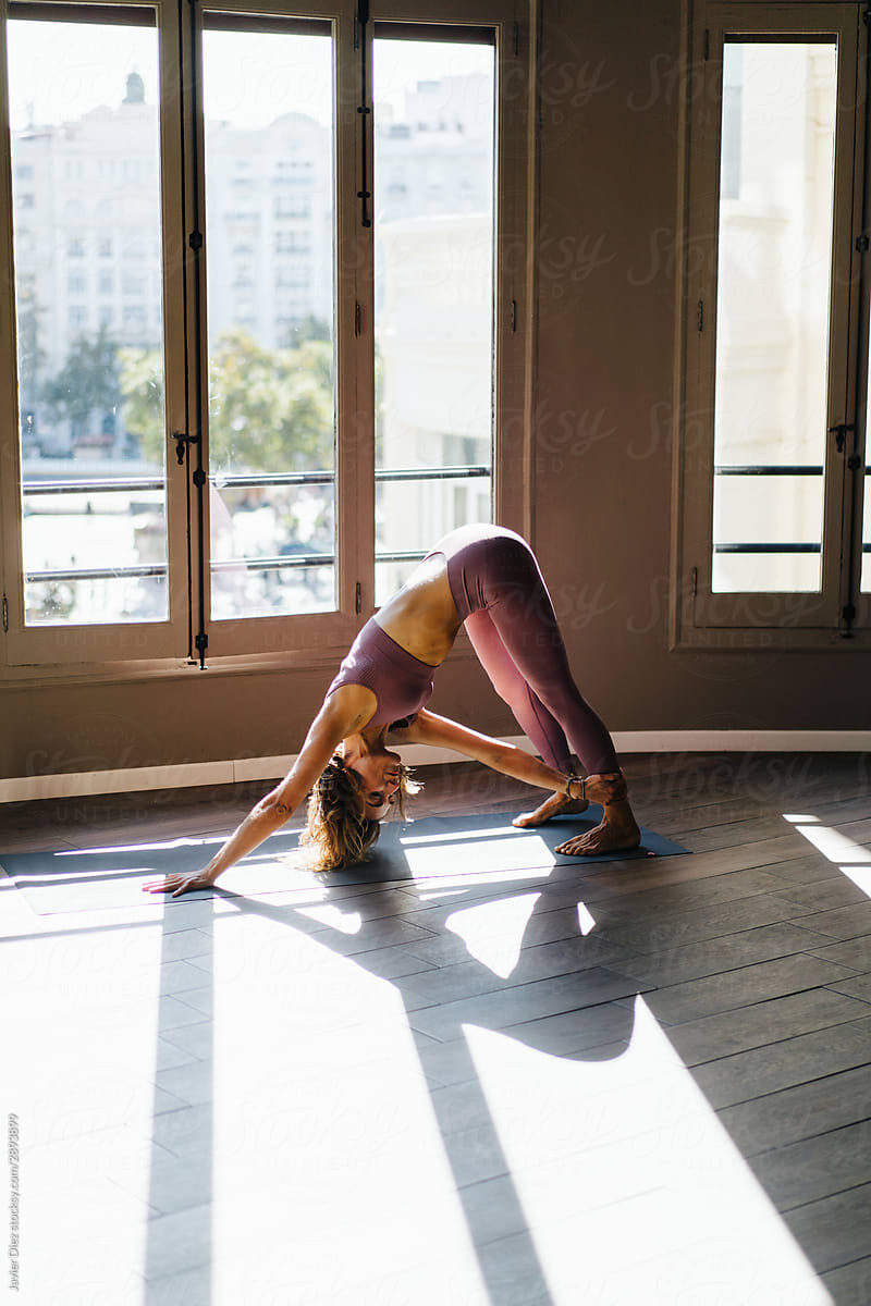 Slim woman doing yoga against window