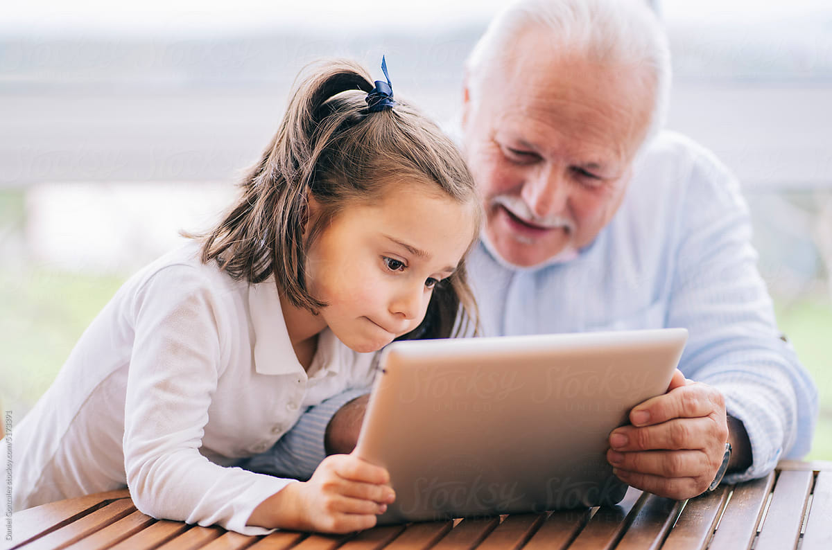 Happy grandfather using tablet with granddaughter